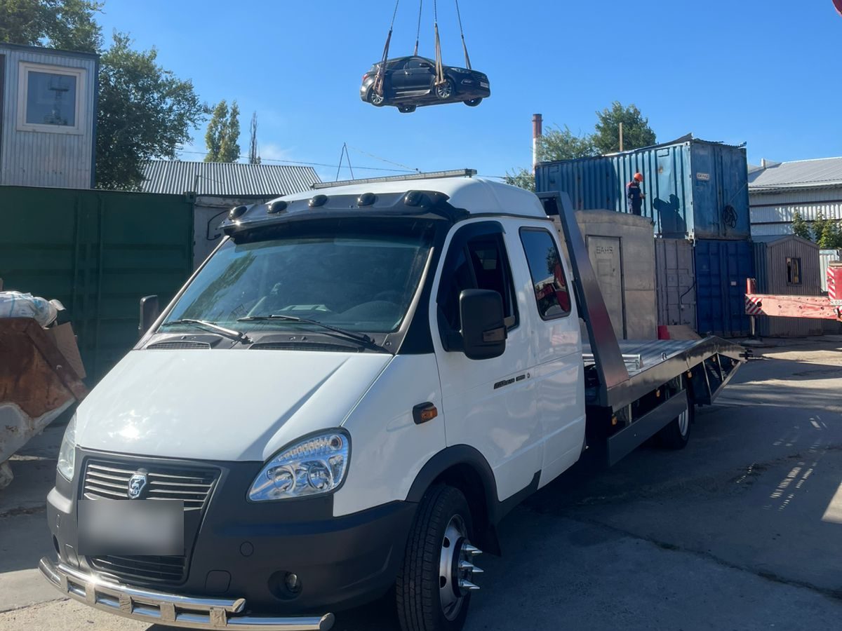 Погрузка автомобиля краном рядом с эвакуатором